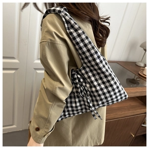 Close-up of black and white checkered tote bag featuring a decorative side bow detail