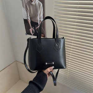 Classic black matte leather handbag with adjustable strap in natural lighting