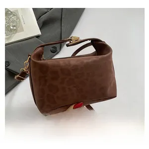 Detail of leopard print handbag with gold hardware next to art book and grey blazer