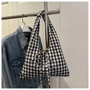 Close-up of black and white checkered tote bag featuring a decorative fabric bow tie