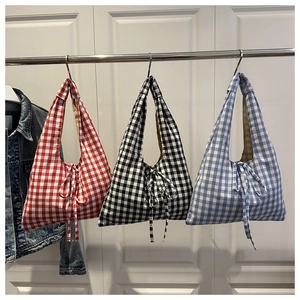 Detailed view of three plaid tote bags in red, black and blue with bow ribbon knots
