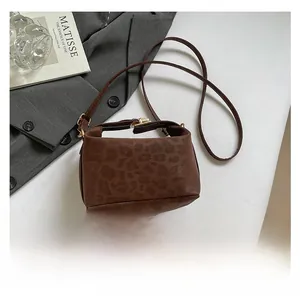 Detail of leopard print handbag with golden hardware and slim shoulder strap