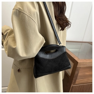 Detail of black quilted leather handbag showing suede stitching and metal chain strap