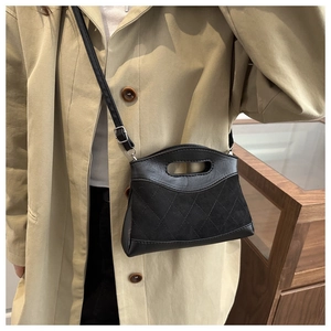 Detail of black quilted patchwork handbag with sleek oval handle and long shoulder strap