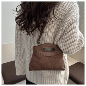 Detail of suede and leather patchwork handbag with rhombic stitching and metal buckle