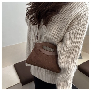 Brown quilted suede tote with unique hollow handle worn over a cream knit sweater