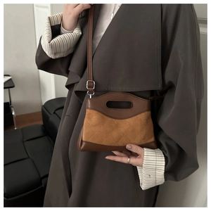 Detail of suede patchwork handbag with diamond stitching and oval handle on a long coat