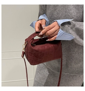 Detail view of burgundy animal texture handbag with golden hardware and zipper ring