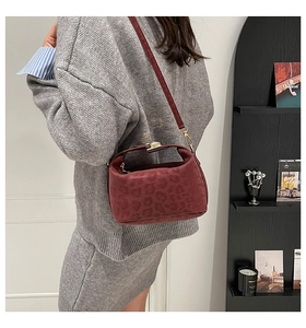 Detail of burgundy leopard print handbag with golden metal buckle and velvet texture