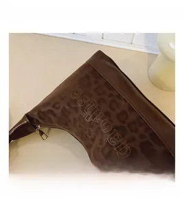 Macro detail of leopard print fabric and leather trim with embossed logo and gold zipper