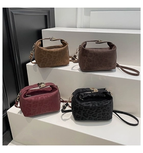 Detailed display of four leopard print handbags in brown, burgundy, and black on a white stand