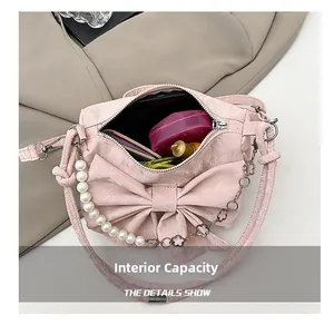 Dettaglio della capacità interna della borsa rosa con fiocco, perle e trucchi inclusi