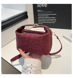 Detail of burgundy leopard embossed handbag with gold metal lock and shoulder strap hooks