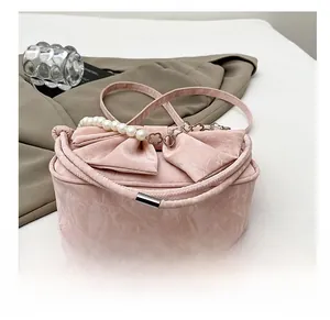 Dettaglio della borsa rosa con fiocco, manico di perle e base resistente all'usura