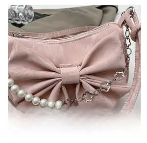 Dettaglio della borsa a tracolla rosa con fiocco, perle e catena in metallo floreale