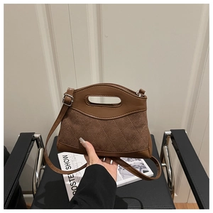 Close-up of brown quilted suede handbag with polished leather trim and metal hardware details