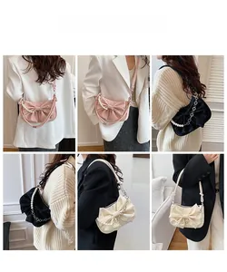 Dettaglio borsa con fiocco e catena di perle indossata a tracolla e a spalla con stile