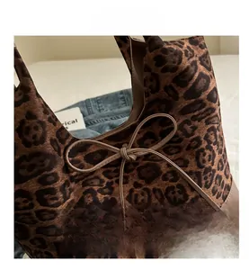 Close-up of leopard print tote bag with suede texture and a delicate leather bow detail