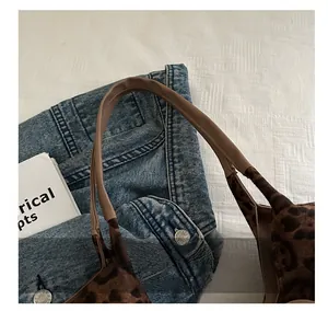 Detail of leopard print tote with brown leather handle and fine stitching on fabric