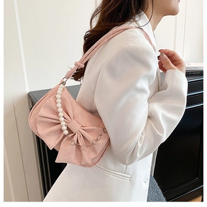 Dettaglio borsa rosa con fiocco, tracolla di perle e trama in ecopelle di qualità