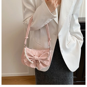 Dettaglio della borsa rosa con fiocco, catena di perle bianche e tocchi floreali