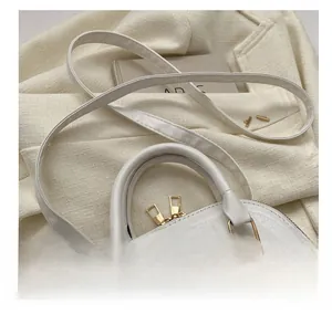 Detail of white quilted handbag featuring gold hardware and adjustable strap