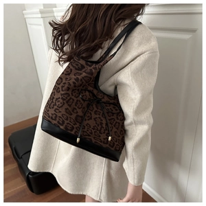Detail of leopard print tote bag with black leather base and decorative bow accent