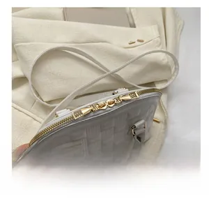 Detail of white textured shell bag with smooth gold double zippers and weave pattern