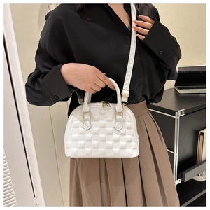 Close-up of a white quilted shell handbag with gold hardware and a detachable strap