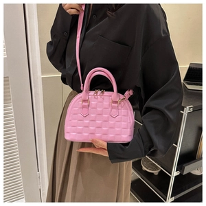 Pink shell handbag with embossed check pattern and gold-tone zippers shown on model