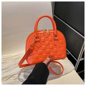 Detail of orange shell handbag with embossed pattern, top handles and gold hardware