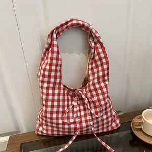 Minimalist red and white gingham tote bag with bow detail on a rustic wooden table