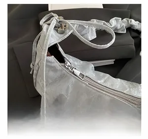 Dettaglio borsa a mezzaluna argento con zip in metallo e trama plissettata metallica