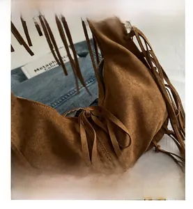 Close-up of brown suede shoulder bag featuring bohemian tassels and tied bow detailing