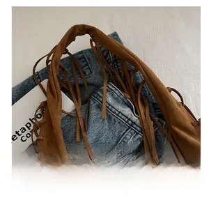 Detailed close-up of brown suede hobo bag with fringe tassels and soft handle design