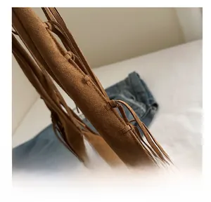 Macro view of hand-woven edges and knotting details on a brown suede shoulder bag
