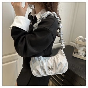 Dettaglio borsa hobo argento con farfalla metallica e ampia tracolla plissettata di tendenza