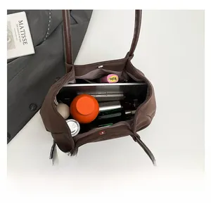 Detail showing high-capacity interior of brown tote bag with laptop and daily essentials
