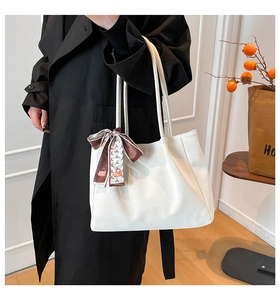 White leather tote bag with decorative silk scarf styled with a long black trench coat