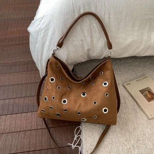 Brown suede shoulder bag featuring stylish silver metal eyelets and a versatile leather strap
