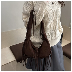 Detail of a brown suede hobo bag with long fringes styled on a woman shoulder