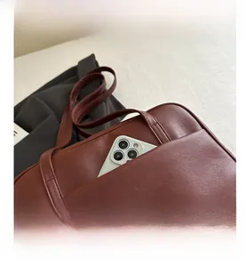 Close-up of retro PU leather tote bag with functional front pocket holding a smartphone