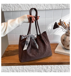Detail of large brown matte tote bag with silk scarf accessory and thin handles