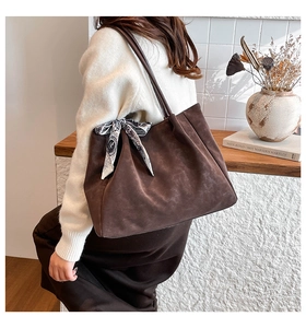 Detail of dark brown matte suede tote bag with decorative silk scarf and pleated texture