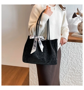 Detail of matte black tote bag featuring fine leather strap and elegant silk scarf accent