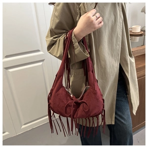 Close-up of a burgundy suede hobo bag featuring long fringes and a bohemian bow detail
