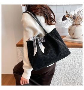 Detail of matte black suede tote bag with printed silk scarf and long shoulder straps