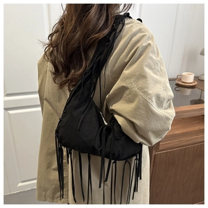 Detail of long black tassels on a large capacity hobo bag worn by a model