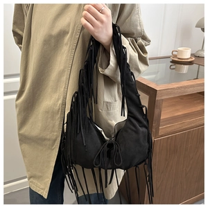 Detail of black crescent hobo bag with long fringe tassels on shoulder strap