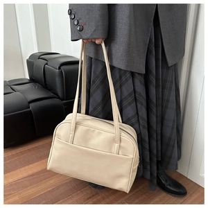 Detail of a beige PU leather tote bag with external pocket and sleek shoulder straps